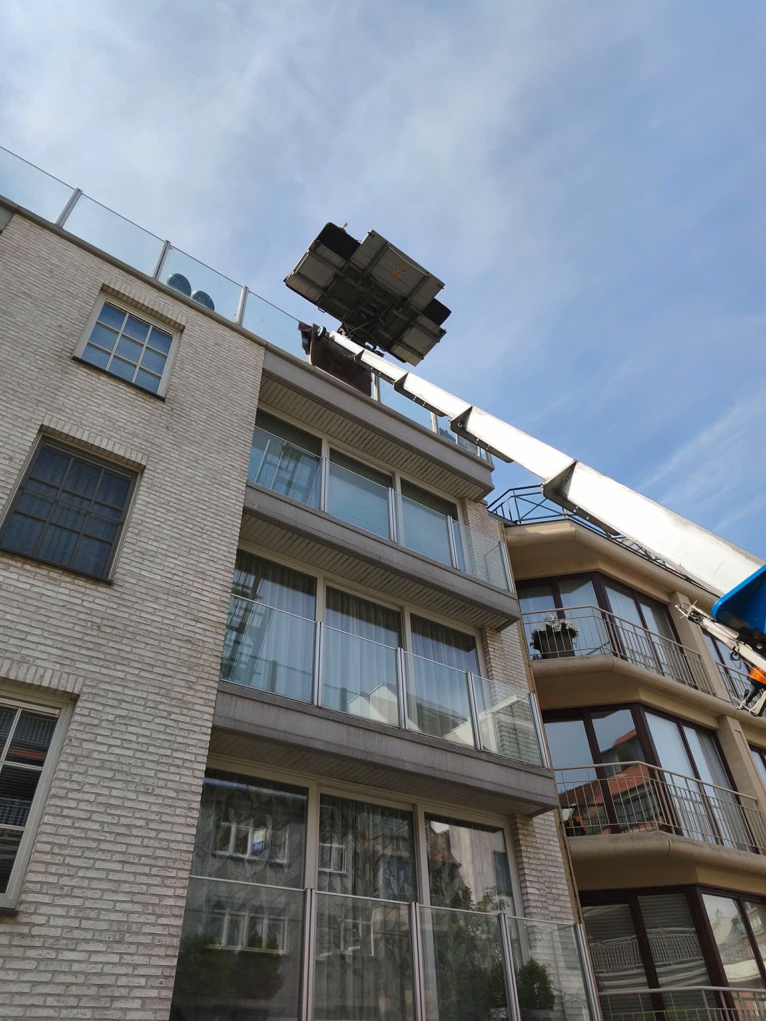 Vue en contre-plongée du monte-meubles Croughs : plateforme chargée arrivée à la terrasse du dernier étage d'un immeuble