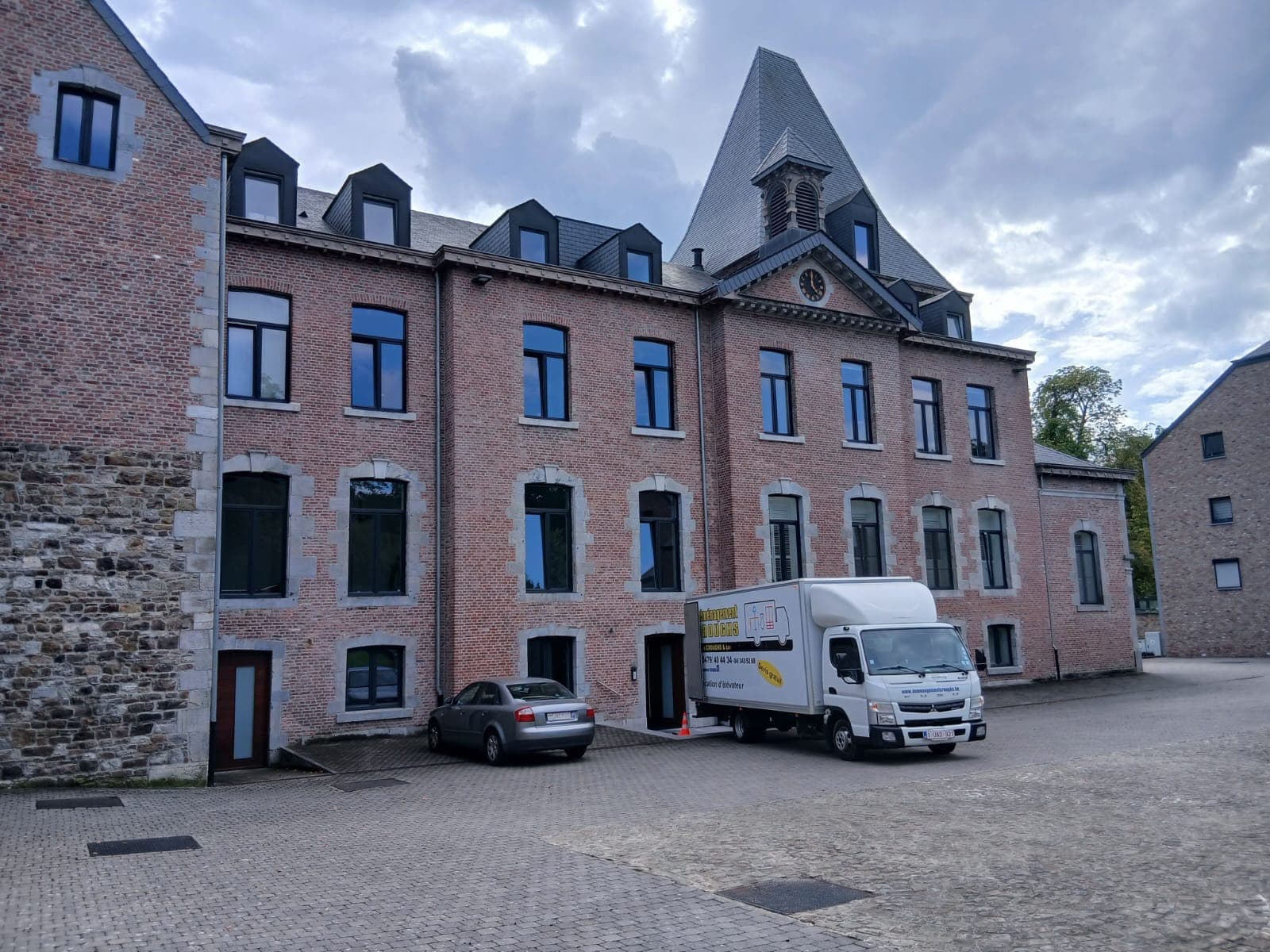 Petit camion Croughs Déménagement garé dans la cour pavée d'un grand bâtiment en briques