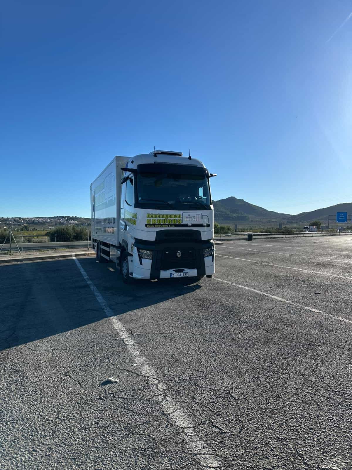 Camion Déménagement Croughs à l'arrêt sur une aire d'autoroute, sous un grand ciel